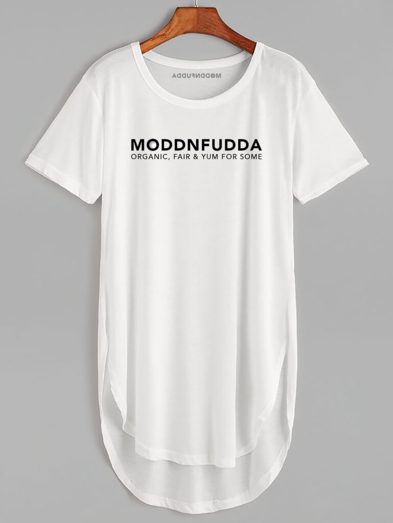 Weißes T-Shirt des Öko-Labels Moddnfudda auf einem Holzbügel. Das T-Shirt trägt die Aufschrift: Moddnfudda – organic, fair and yum for some